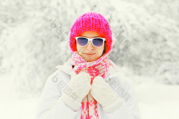 时尚冬季肖像年轻女子戴着五颜六色的针织帽子，戴着雪背景上的太阳镜