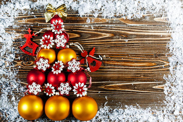 圣诞树，内衬红色和金色的圣诞树球。 圣诞树玩具躺在木头表面上。 树旁边是a