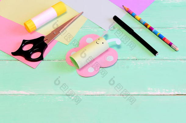 有趣的纸蝴蝶工艺品，剪刀，记号笔，胶水棒，铅笔，彩色纸，绿色木制背景上的铅笔