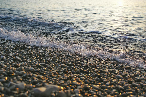 日出时卵石滩上迎面而来的海浪冲浪的抽象背景