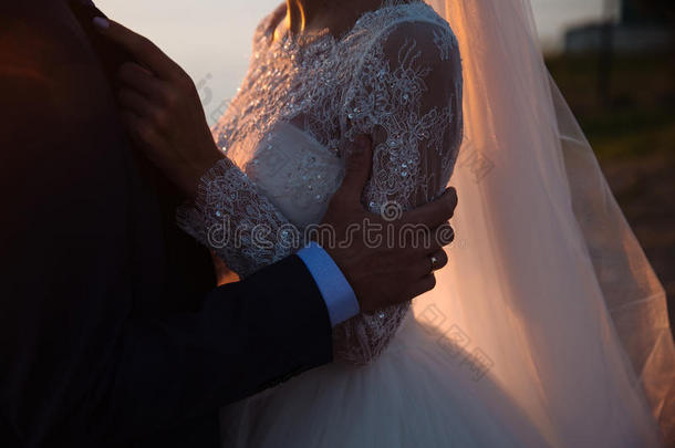 新郎和新娘在日落时牵着手，婚礼当天。 爱家庭的概念