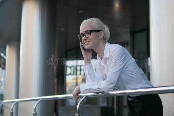 漂亮的年轻女商人戴着眼镜的金发女孩在后台商务中心打电话