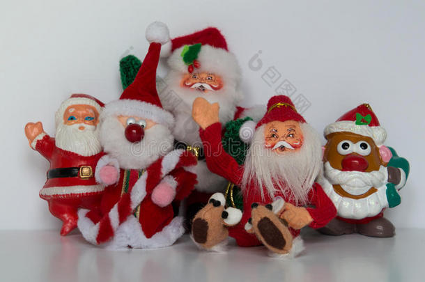 五个圣诞老人的装饰品，四个站着，一个坐着，向镜头挥手。