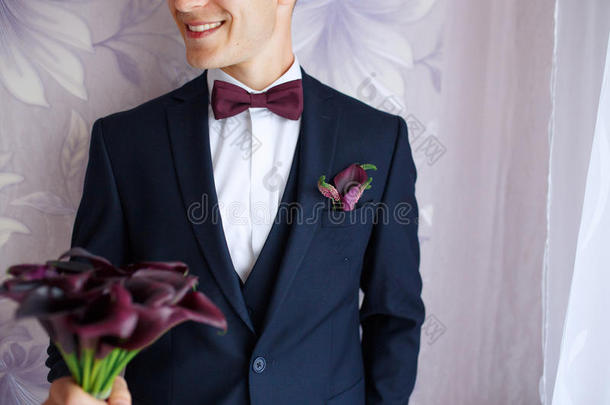 华丽微笑的新郎。 英俊的新郎在婚礼上，燕尾服微笑着等待新娘。穿着黑色服装和领结的优雅男人。