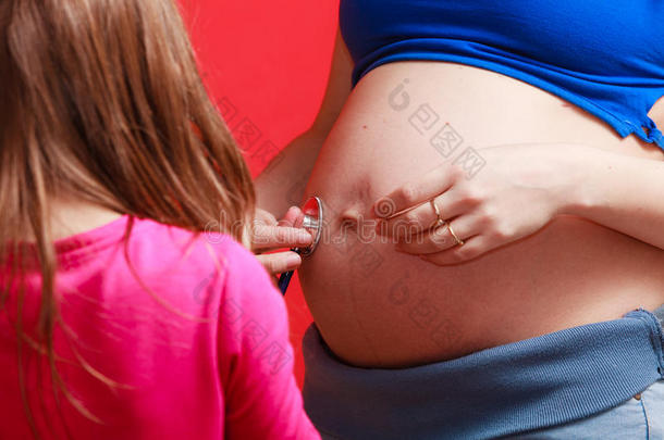 女儿看着怀孕的妈妈大肚子