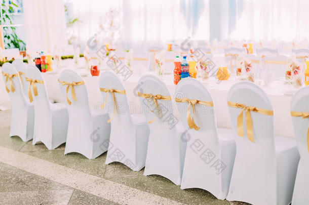 节日餐桌上<strong>椅子</strong>上装饰的白色壁炉架和彩色<strong>丝带</strong>。