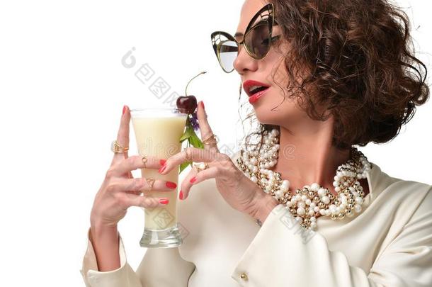 卷曲的时尚女人，手里拿着PinaColada鸡尾酒，开心地笑着，戴着迷人的太阳镜笑着