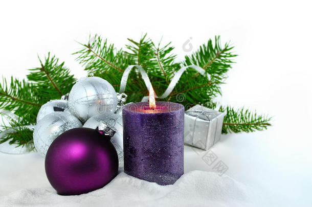 带有蜡烛和装饰品的圣诞节背景。 紫色和银色的圣诞球在雪中的冷杉树枝上