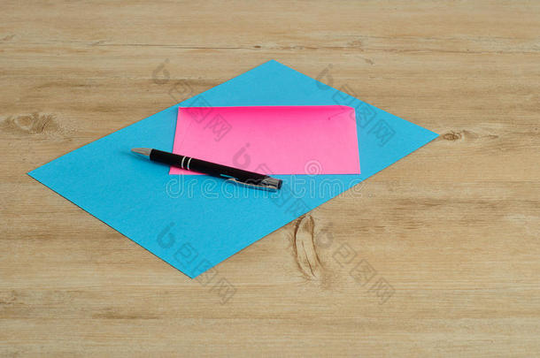 蓝色的纸和一个带黑色钢笔的粉红色信封