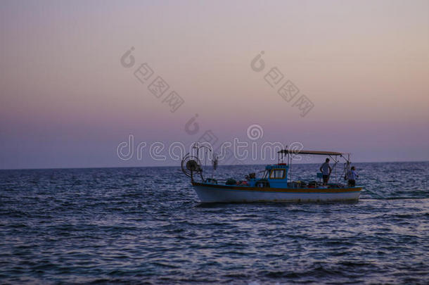 日落时，船上的渔民渔民。 渔民收集他们的网。 商船的轮廓