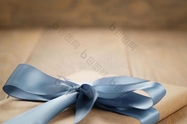 手工礼品棕色纸盒与蓝色丝带蝴蝶结在木桌上