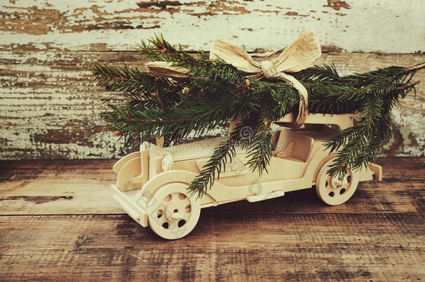 儿童`的木制<strong>汽车</strong>是幸运的杉树枝背景下的一个古老的古董板。 载有圣诞<strong>节</strong>的木制<strong>汽车</strong>