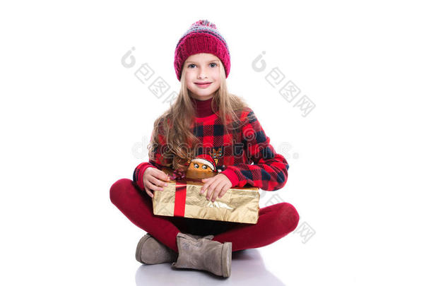 可爱的微笑小女孩，卷发，穿着针织毛衣，围巾和帽子，拿着圣诞礼物，白色的