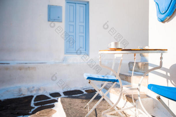 美丽的咖啡馆在一条街道上，典型的希腊传统村庄Mykonos岛，希腊。 早餐在桌子上喝咖啡