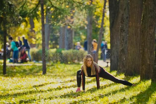 健身女子力量训练，在阳光明媚的秋天公园锻炼。 适合白种人运动女孩锻炼她的身体