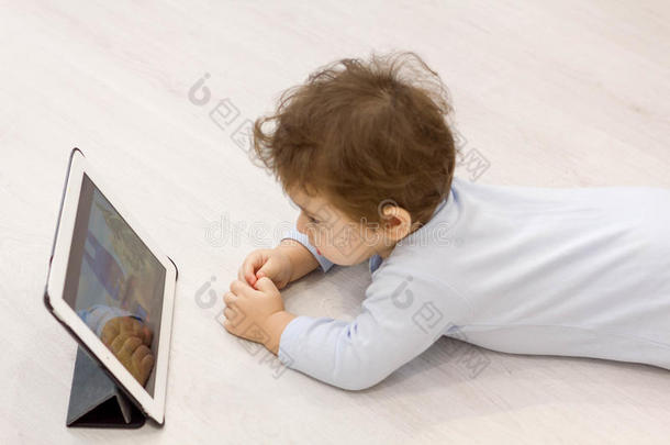 孩子在平板电脑上看卡通，背景是他不想玩的玩具