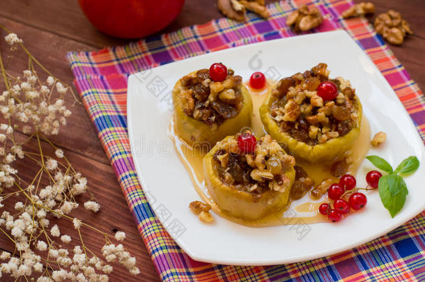 用葡萄干、核桃和蜂蜜做甜点的烤苹果。木质质朴的背景。特写镜头。俯视图
