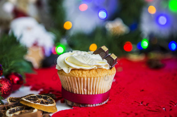 蛋糕，放在一张白色的木制桌子上的红色圣诞餐巾上，桌子周围有绿色的花环和圣诞灯