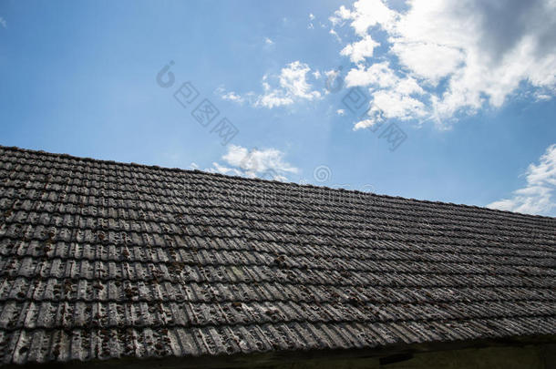村里老房子上的旧瓦。青云密布的天幕映衬下，小屋瓦房屋顶上长满了青苔。乡村风光