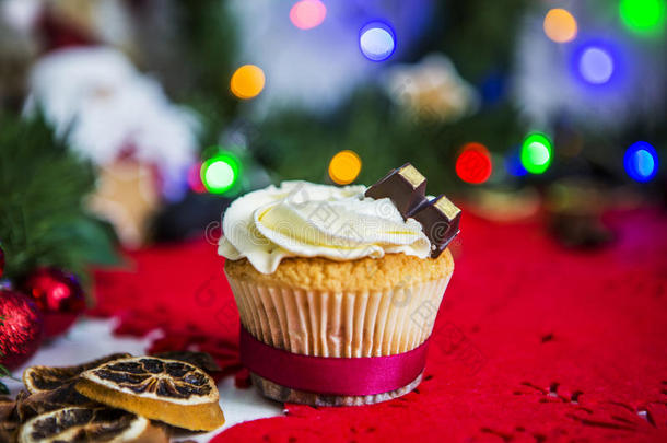 蛋糕，放在一张白色的木制桌子上的红色圣诞餐巾上，桌子周围有绿色的花环和圣诞灯