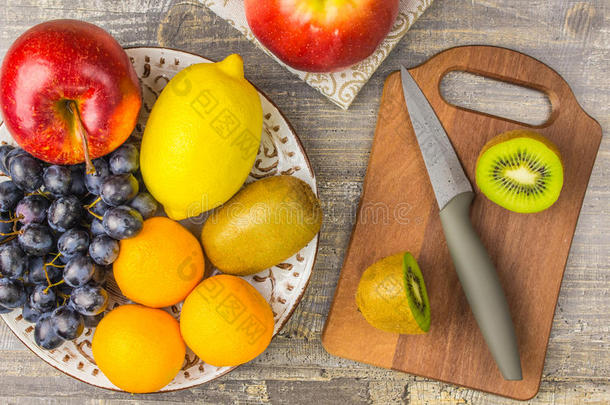 苹果橙，柠檬，水果，猕猴桃，盘子和木板。把葡萄背景放在桌子上。