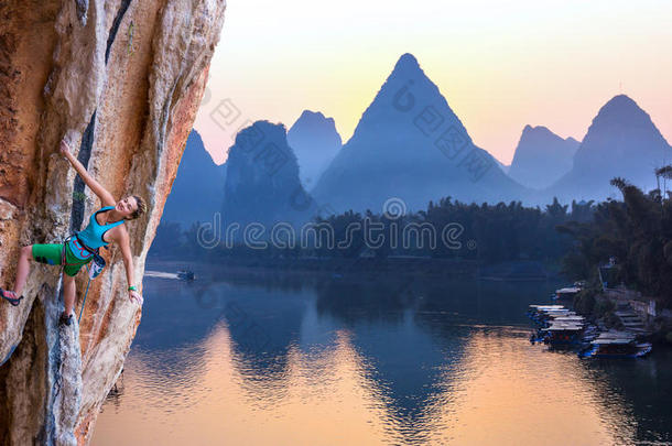 年轻攀岩者日出喀斯特山在中国和河流的明亮形象