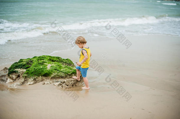 小男孩在海边的沙滩上散步。 可爱的孩子在沙滩热带海滩。