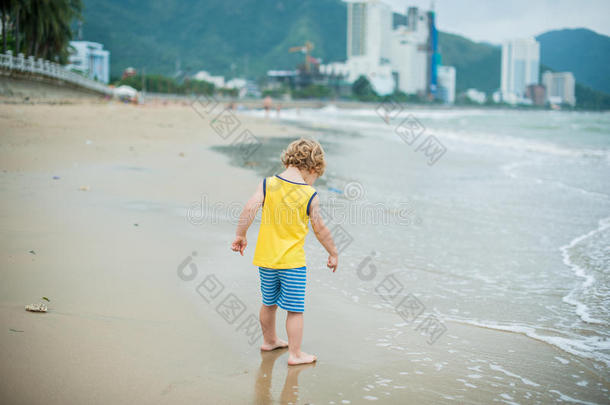 小男孩在海边的沙滩上散步。 可爱的孩子在沙滩热带海滩。