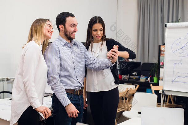 一群四个不同的快乐的同事在小办公室拍自我肖像，用手做有趣的手势