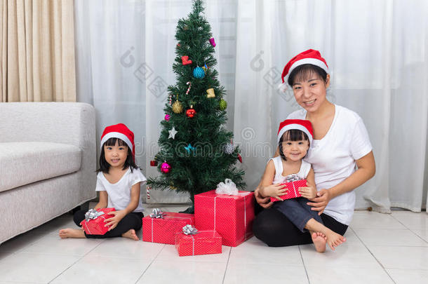 亚洲的中国母亲和女儿坐在圣诞树旁边