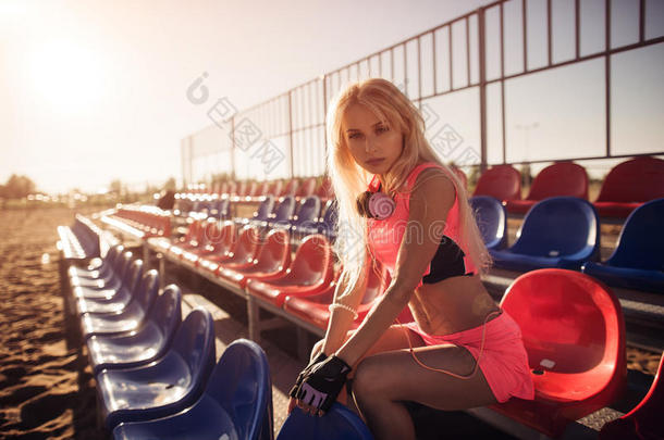 迷人的女运动员坐在海滩上休息后，密集的排球比赛，夏季背景