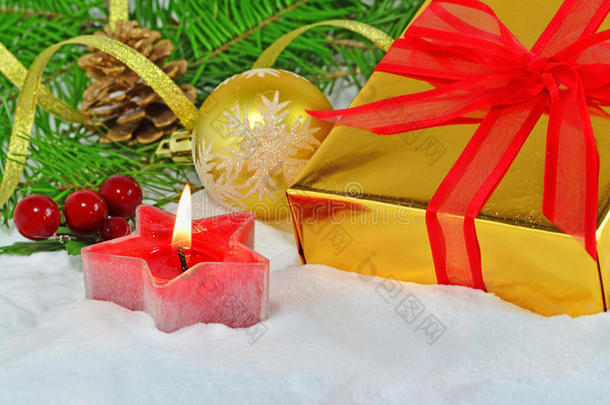 金色的礼物，红色的蝴蝶结和蜡烛，圣诞装饰在雪地上