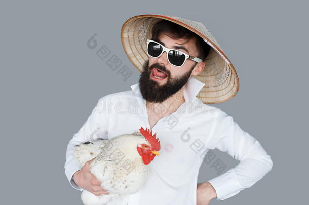 留胡子的人穿着白色衬衫拿着一只鸡