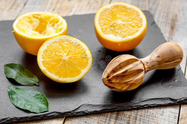 把橘子切成两半，在木制背景上用<strong>榨汁机</strong>榨汁