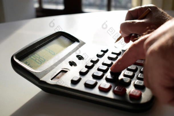 在办公室工作的商人在工作场所用计算器。