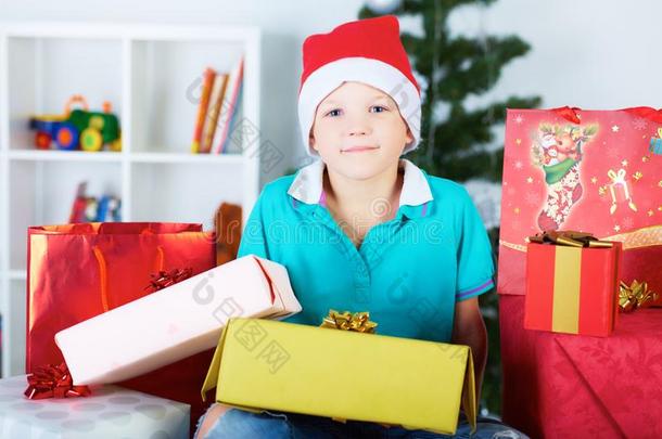 男孩靠近圣诞树和礼品盒，快乐的假期和冬天的庆祝活动。