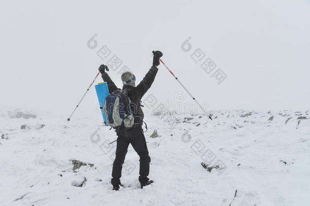 极限运动。 孤独的徒步旅行者在冬天的山上站在山顶上，举起了哈兹