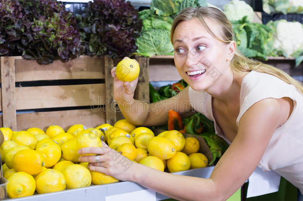 友好的女人在水果店手里拿着柠檬