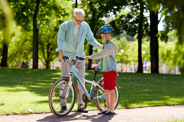 祖父和男孩在夏季公园骑自行车