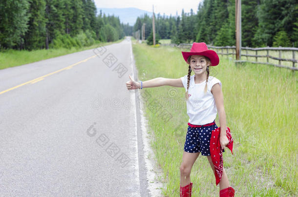 可爱的小牛仔试图搭便车在一条孤独的路上