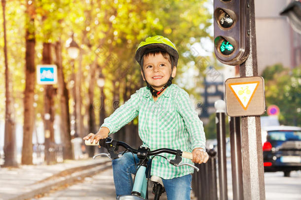 可爱的男孩骑着他的自行车在绿色的灯光信号上