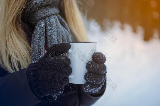 戴手套的手拿着旅行杯。 冬季森林雪的背景。