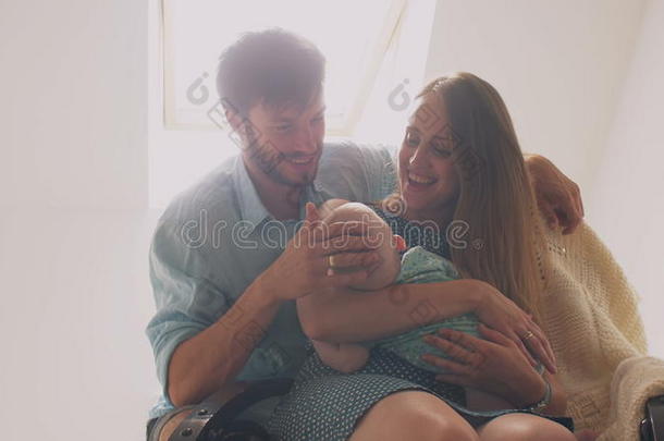 美丽幸福的家庭母亲把她的孩子放在摇椅上，父亲拍拍儿子的头，亲吻妻子。 4k