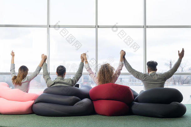 开朗的商人团体在同事中心团队的同事举手坐在前面的大全景窗口