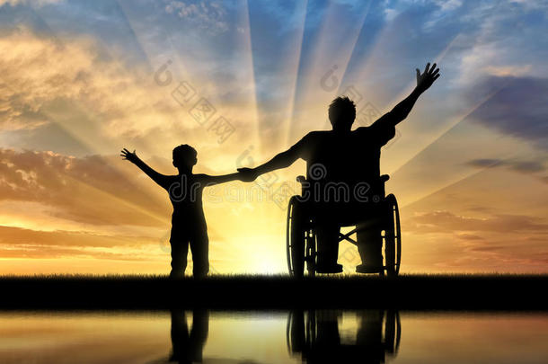 残疾人在轮椅上和他的儿子是快乐的，他们的反思日落