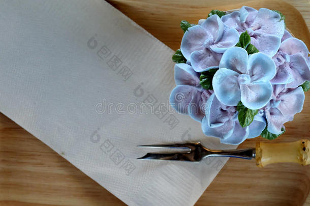 蓝色纸杯蛋糕设计奶油，如蓝色绣球花，用棕色纸巾和小叉子放在木托盘上