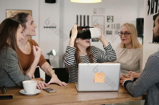 第一次体验虚拟现实眼镜，年轻的团队支持年轻美丽的黑发女孩在现代创业办公室