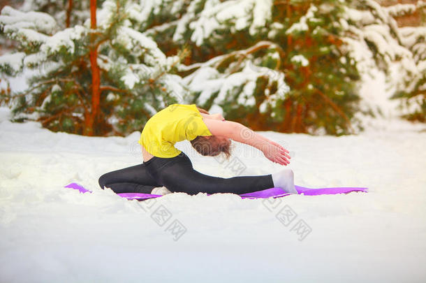 美丽的女人在雪地里户外做瑜伽