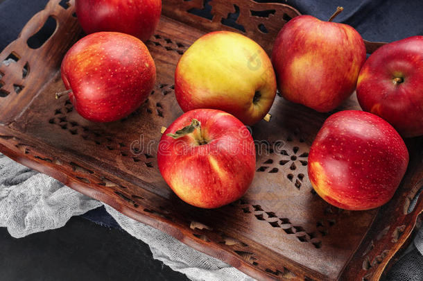 新鲜的红苹果放在蓝色桌子上的木制托盘里