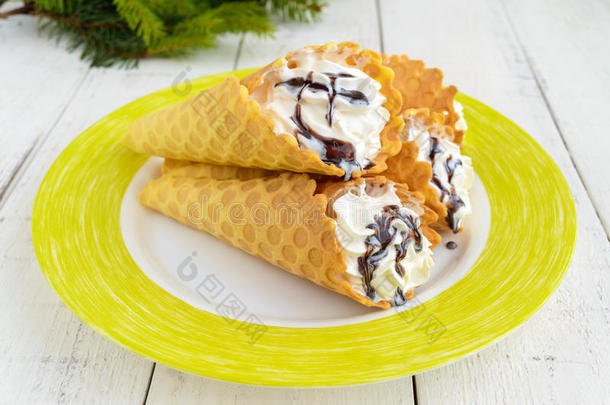 酥脆的蜂蜜晶片，以圆锥形的形式，充满空气香草奶油冰淇淋与巧克力糖浆顶部